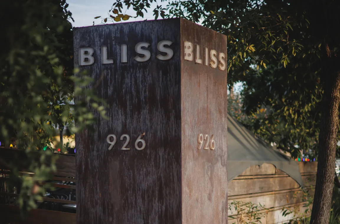 Weathered steel entrance sign displaying "Bliss" and the street number 926, marking the entrance to Bliss restaurant in San Antonio.
