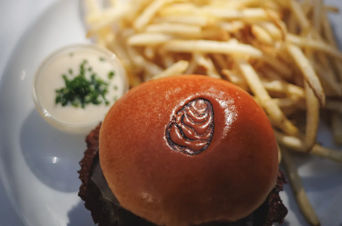 Crispy fried chicken sandwich on a toasted brioche bun with seasoned fries and dipping sauce, served at Little Em's Oyster Bar.