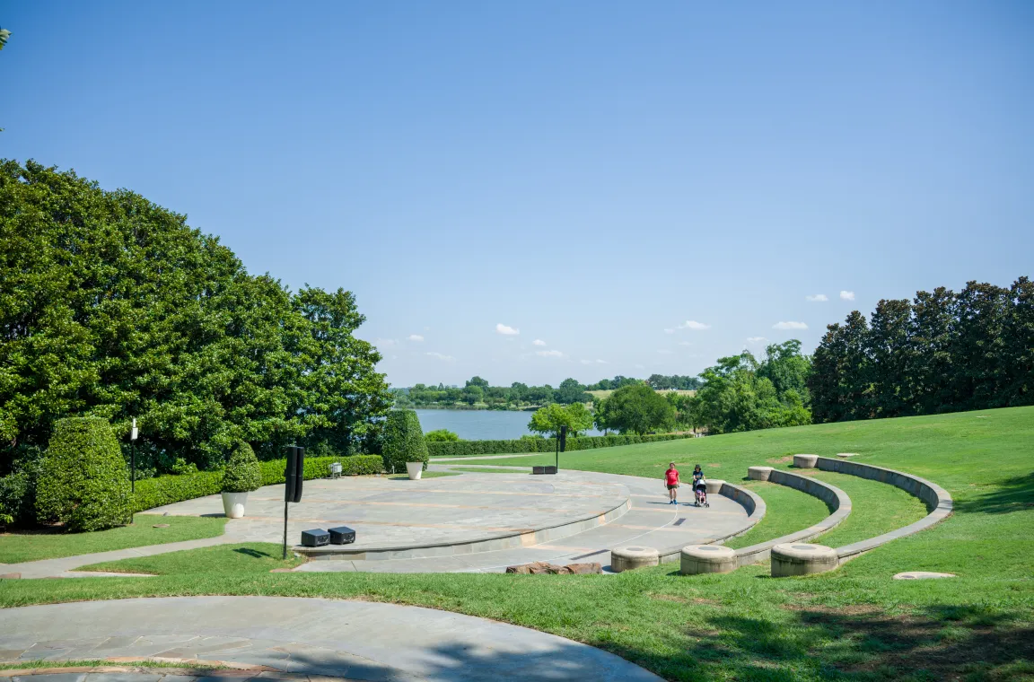 An open lawn with a terraced amphitheater overlooking White Rock Lake, offering scenic views and outdoor gathering space.