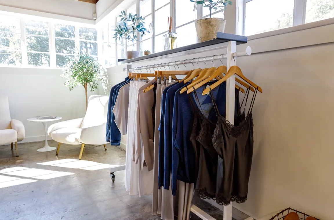Clothing display inside Abejas Boutique showcasing women's apparel on a minimalist clothing rack in a bright, modern retail space.