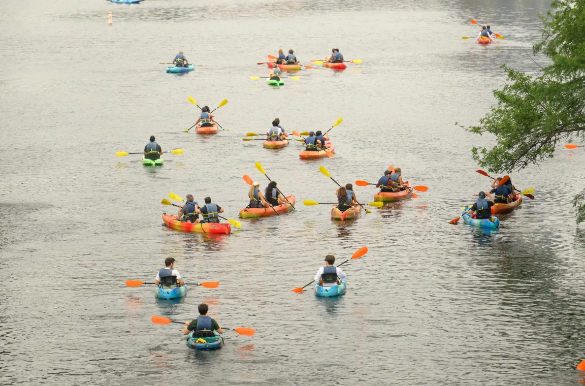 Colorful kayakers paddling across Lady Bird Lake, showcasing one of Austin’s most popular outdoor recreation destinations.