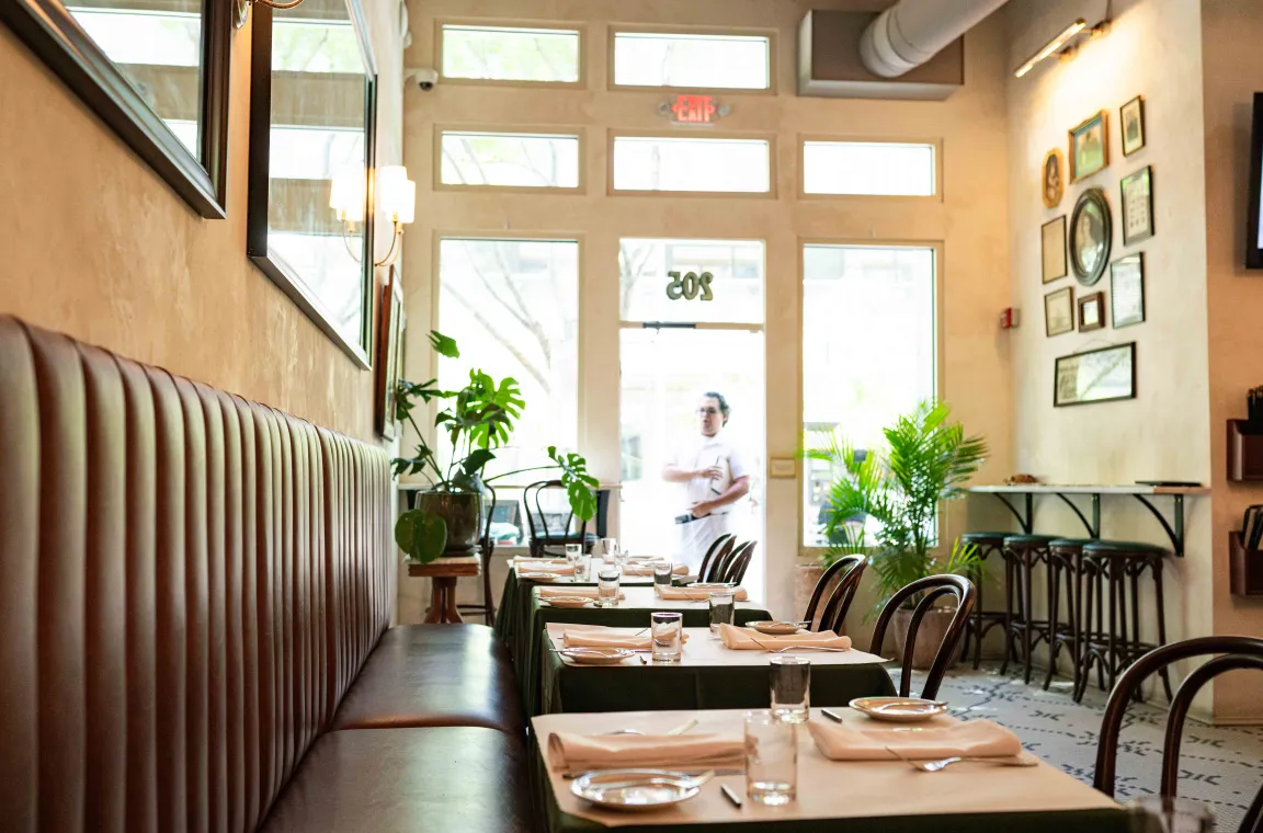 Interior dining room of Bill's Oyster House featuring cozy booth seating, neatly set tables, large front windows, and a bright, welcoming atmosphere.