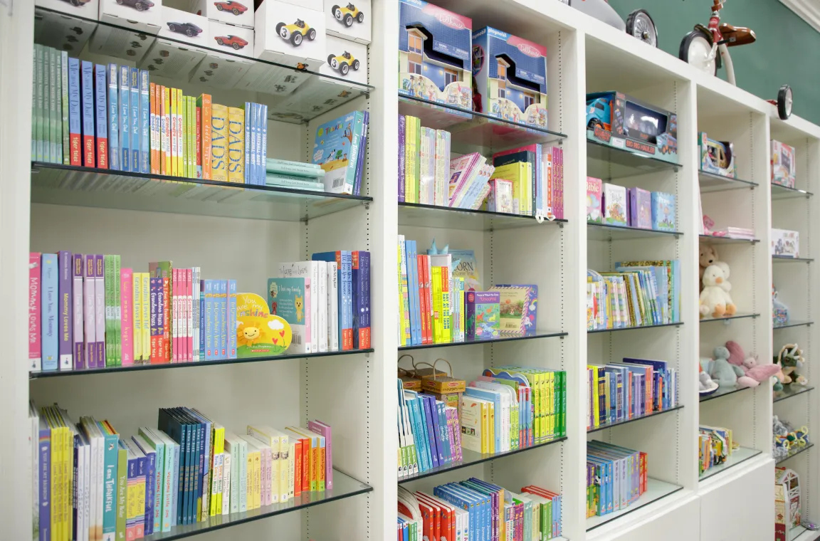 Books, toys, and children's gift display inside Bering's Hardware & Gifts with shelves of storybooks, games, and plush animals.