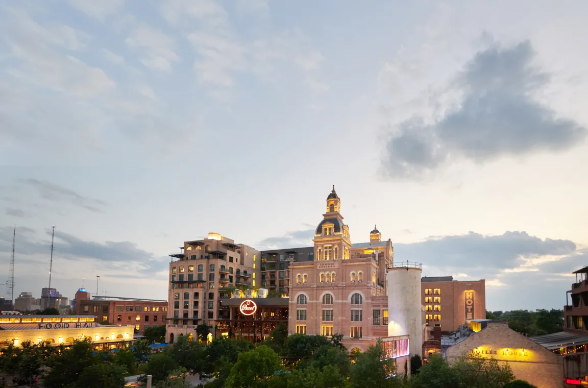 Twilight panorama of the Pearl district in San Antonio, showcasing the illuminated brewery complex against a dramatic evening sky.