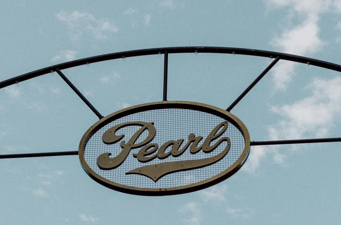 Vintage-style Pearl entrance sign suspended against a blue Texas sky at the Pearl district in San Antonio.