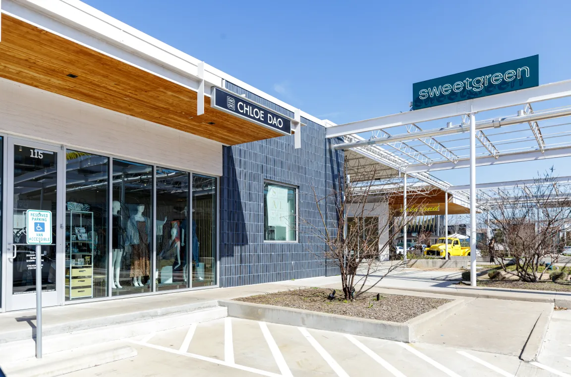 Exterior storefront of the Chloe Dao boutique in Houston, featuring a modern glass facade, blue-tiled walls, and a wood-paneled overhang, located next to a sweetgreen restaurant.