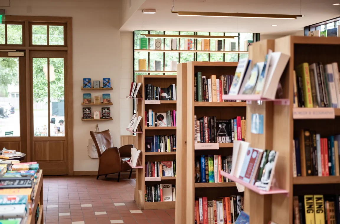 Bookshelves filled with curated titles at First Light Books, featuring bright natural light, comfortable seating, and a welcoming browsing atmosphere.