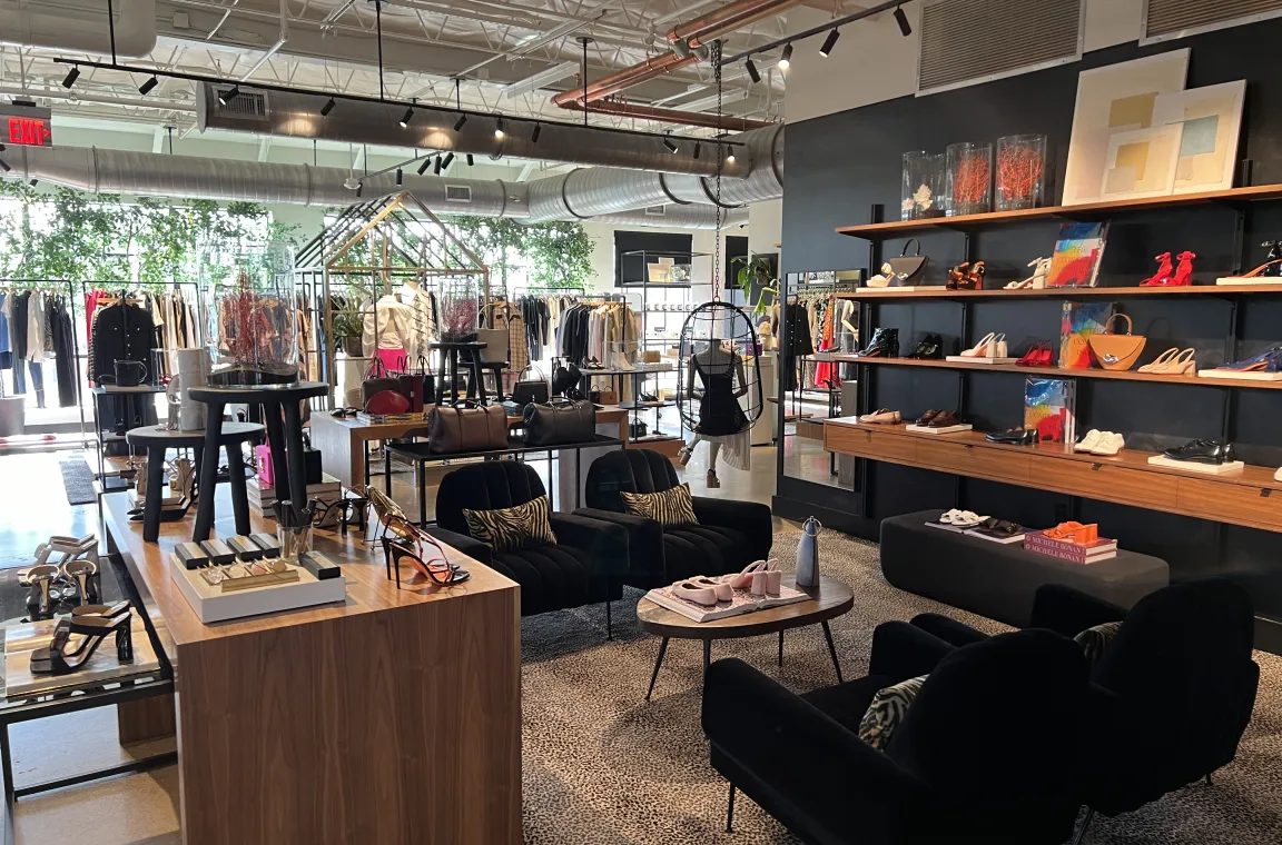 Interior of The Conservatory at Highland Park Village showcasing designer clothing, handbags, shoes, and accessories in a modern luxury retail space.