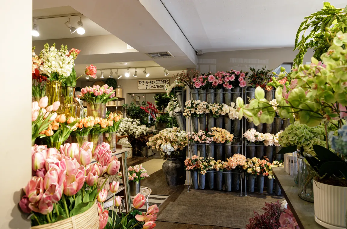 An indoor floral department display filled with multi-colored faux tulips, hydrangeas, and roses arranged in wall-mounted buckets and baskets.
