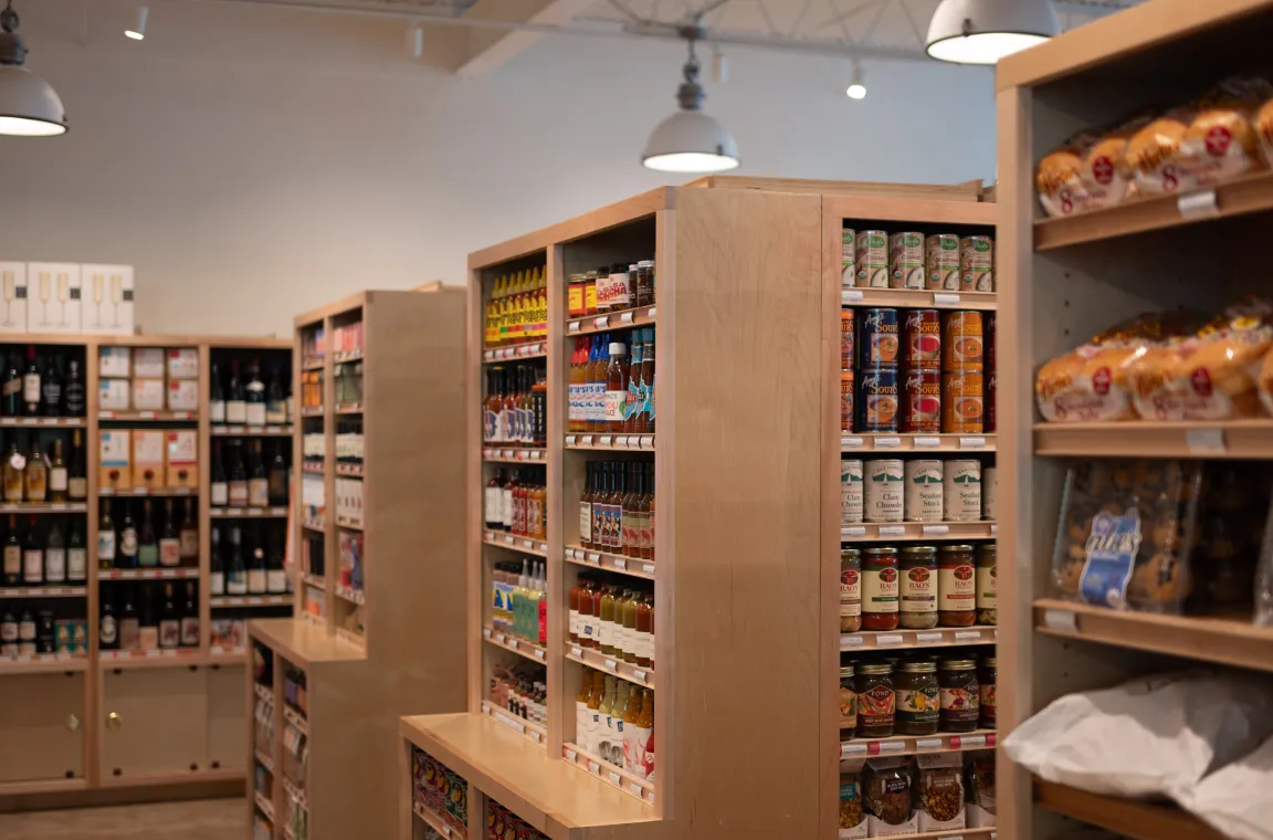 Interior of Tiny Grocer featuring shelves stocked with specialty groceries, wine, pantry staples, and fresh baked goods.