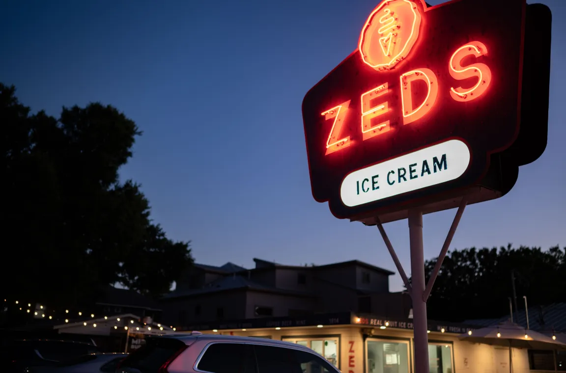 Neon roadside sign for Zed's Real Fruit Ice Cream glowing against the evening sky.