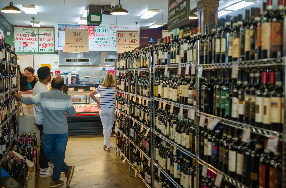 Customers browse wine shelves leading to the fresh meat and sausage counter inside Jimmy's Food Store, a longtime Italian market and deli in Dallas.