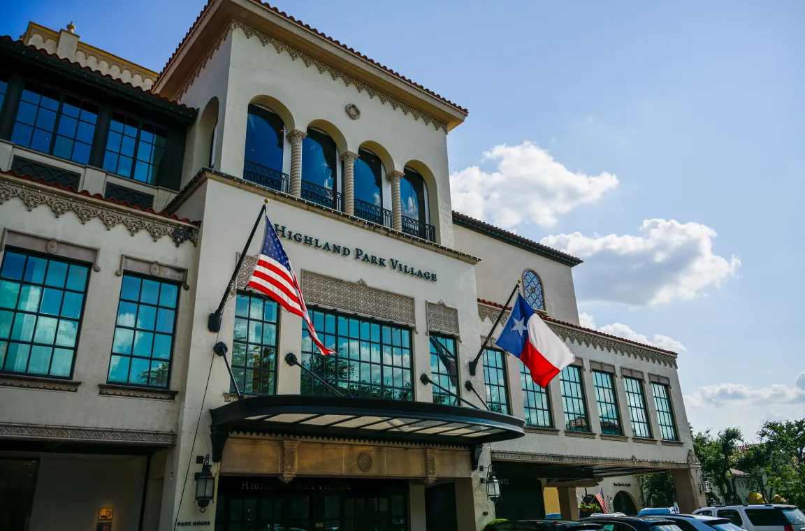Highland Park Village entrance featuring Spanish Revival architecture with American and Texas flags displayed above the main entrance.