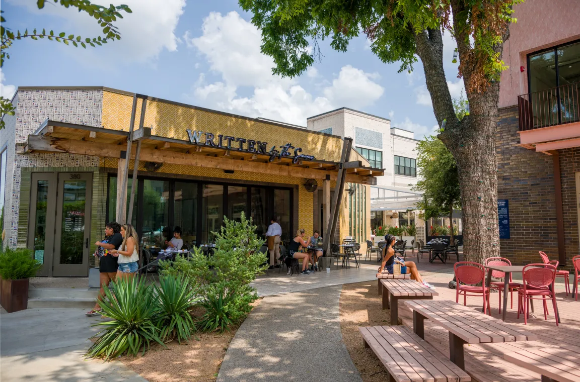 Outdoor dining and gathering spaces outside a neighborhood restaurant, showcasing Bishop Arts' blend of independent eateries, shaded courtyards, and relaxed community atmosphere.